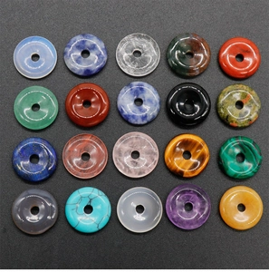 Macro shot of twenty natural stone donut pendants in various colors on black background