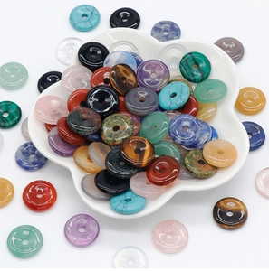 Macro shot of assorted natural crystal donut beads in a white ceramic petal bowl