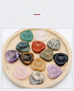 Variety of polished natural gemstone hearts in a wooden tray, featuring amethyst and quartz