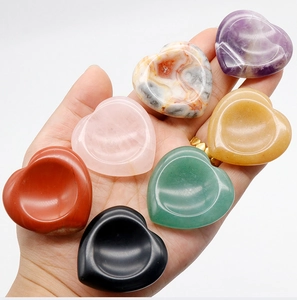 Close-up of assorted heart-shaped natural crystal worry stones held in hand for scale