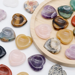 Polished natural heart-shaped crystal worry stones in varied colors on a wooden tray