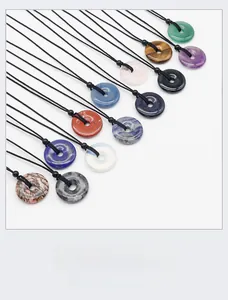Variety of natural crystal donut pendants including amethyst and tiger eye with black cords