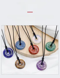 Close-up of various natural crystal donut pendants with woven black cords on a wooden plate