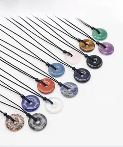 Flat lay of multiple 30mm natural stone donut pendants with black braided cords