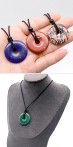 Detailed view of donut-shaped natural stone pendants on neck model with black braided cords