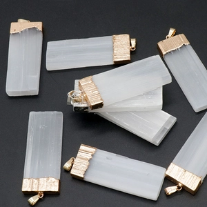 Natural selenite crystal pillar pendants with gold-plated edges on a grey stone background