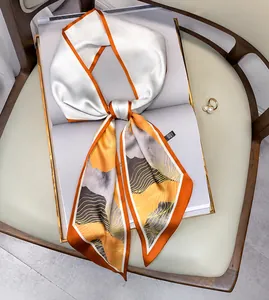 Écharpe longue en soie style peinture à l'huile posée sur un magazine blanc