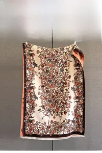 Detail of floral jacquard pattern on cream shawl with fringe and brown trim