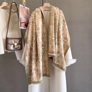 Detail of pink floral cashmere shawl with olive green border and fringed edges on a coat