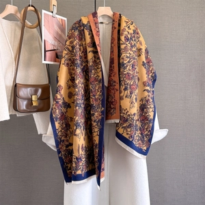 Detail of vintage floral cashmere-like shawl with tassels on a white wool coat