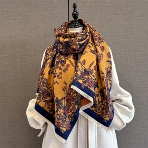 Close-up of mustard yellow vintage floral shawl with fringe tassels over white coat