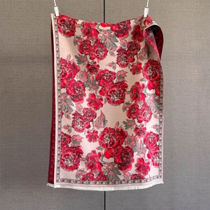 Detail of pink cashmere-like scarf with red peony pattern and fine white fringe
