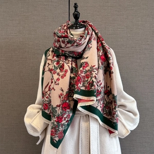 Retro floral cashmere-feel scarf with tassels draped over a beige winter coat