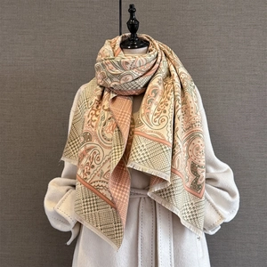 Cashmere feel paisley jacquard scarf with fringe trim worn over a cream coat