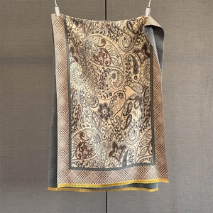 Macro detail of cashmere-like scarf showing yellow fringe and beige paisley pattern
