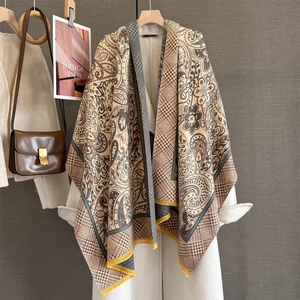 Detailed view of paisley pattern scarf with yellow tassels styled on a white coat