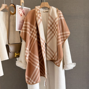 Detail of classic plaid cashmere-like scarf draped over a beige wool coat on a hanger
