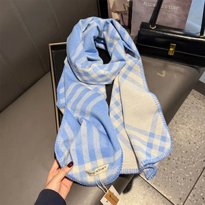 Detailed view of the fine stitched edge and soft texture of a blue plaid cashmere scarf