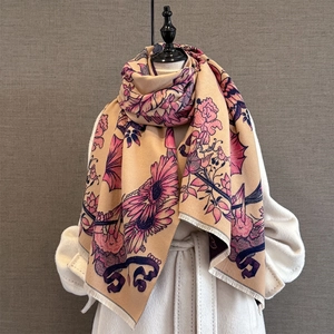 Elegant floral cashmere-feel scarf with tassels draped over a coat on a mannequin