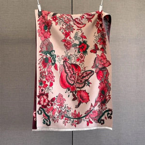 Close-up of pink cashmere-like scarf featuring red floral patterns and fringe details