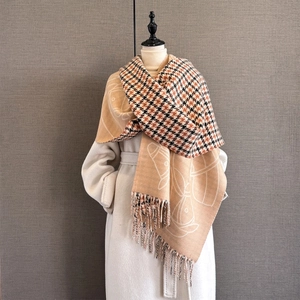 Dettaglio di sciarpa in finto cashmere con motivo pied-de-poule, grafiche e nappe