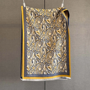 Close-up of yellow paisley cashmere-feel scarf showing intricate jacquard texture and fringes