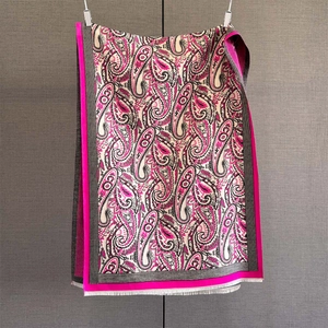 Close-up of paisley pattern knit scarf in rose red and black with delicate white tassels