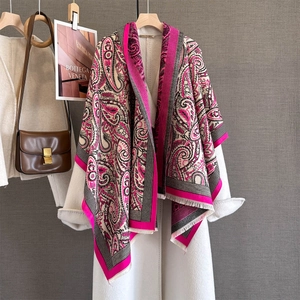 Detail of fuchsia paisley cashmere-feel scarf with tassels over a white coat