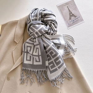 Close-up of grey and white cashmere jacquard scarf with fringe on a beige wool coat