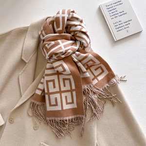Detail of jacquard knit scarf showing brown geometric logo patterns and twisted fringes