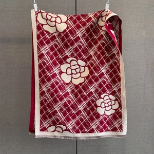 Détail du motif floral camélia rouge et texture à carreaux sur l'écharpe d'hiver chaude