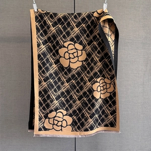 Gros plan sur l'écharpe en tricot avec motif de camélia et franges en noir et doré