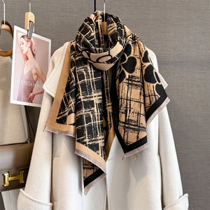 Détail d'écharpe pashmina à rayures jaunes et motifs floraux sur un manteau de laine