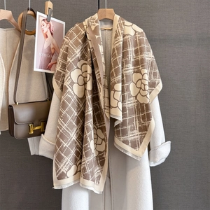 Détail d'une écharpe rayée beige et marron avec motifs camélia et franges délicates