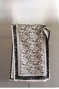 Detail eines schwarz-weißen Schals mit Muschel-Jacquardmuster und feinen Fransen