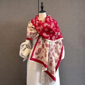 Close-up of red and beige paisley jacquard scarf with fine tassels on white coat