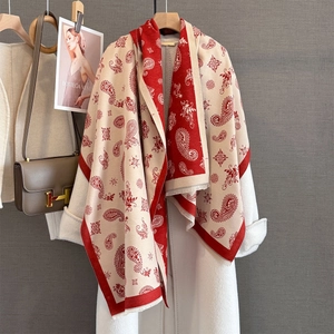 Ethnic paisley jacquard shawl in red and white with fringe on a white coat
