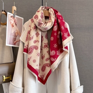Detailed view of red and beige paisley jacquard scarf with decorative fringe borders