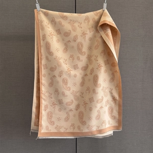 Close-up of beige paisley jacquard scarf with delicate fringe edges and soft texture