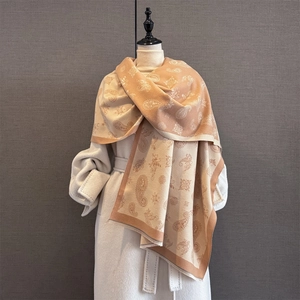 Close-up of caramel paisley jacquard shawl fabric with delicate fringed edges