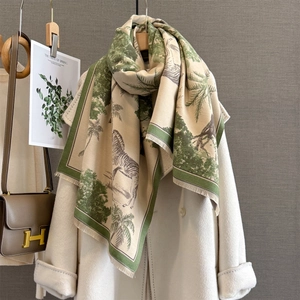 Detail of cashmere-like scarf with zebra and palm tree prints and forest green borders