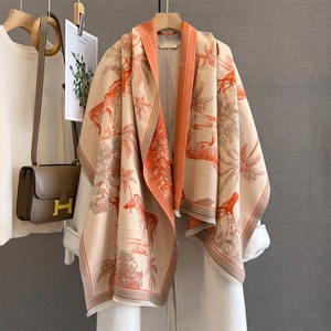 Close-up of beige cashmere shawl with orange zebra and palm tree prints and fine fringe