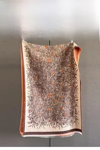 Detailansicht des floralen Jacquard-Musters und der feinen Fransen an einem braunen Schal