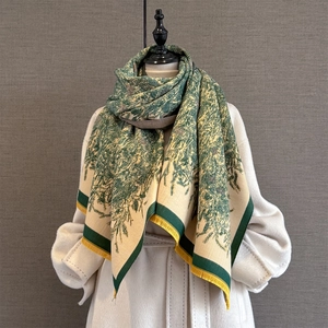 Detail eines Pashmina-Schals mit grünen Zweigen und eleganten goldgelben Fransen