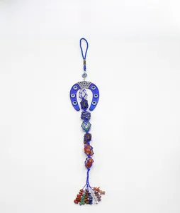 Detail of horseshoe evil eye wall hanging with seven chakra raw crystals and blue fringe