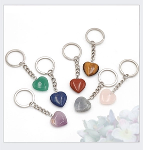 Flat lay of seven heart-shaped natural gemstone keychains in assorted vibrant colors