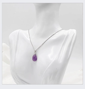 Close-up of a faceted purple amethyst teardrop pendant on a silver necklace for women