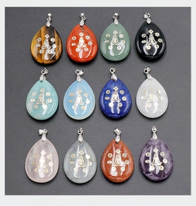 Vue macro de 12 pendentifs en cristal goutte avec symboles dorés de méditation yoga chakra