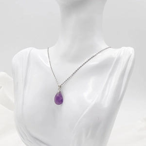 Elegant silver necklace featuring a faceted teardrop amethyst crystal pendant on a white bust