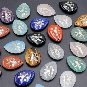 Détail de pendentifs chakra en forme de goutte avec gravure yoga et pierres fines
